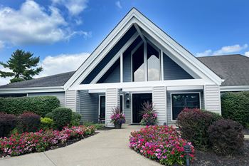 the front entrance of a white house with flowers and bushes at Deercross Apartments, Cincinnati, OH
